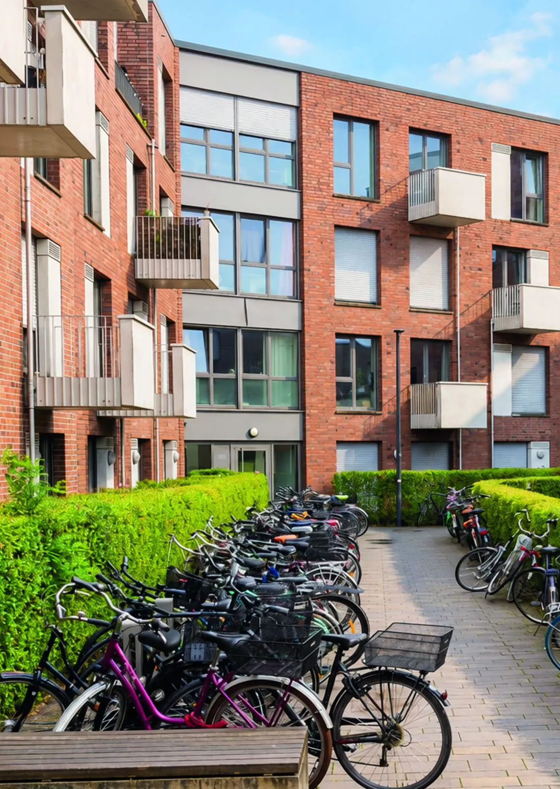 Innenhof des N19 mit Fahrradstellplätzen, Hecken und Klinkerfassaden